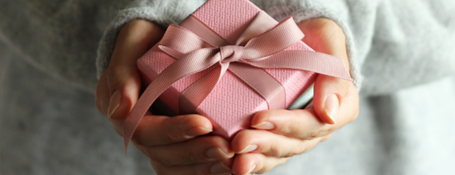 Person holding a small pink gift box in their hands